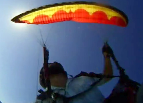 Parapente vermelho fazendo um giro negativo